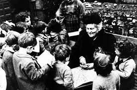 A black and white photo of a woman talking to a group of children.