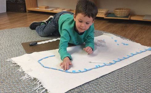 A young boy is laying on the floor playing with a piece of paper.