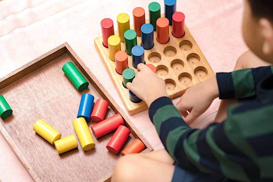 A child is playing with a wooden toy on the floor.