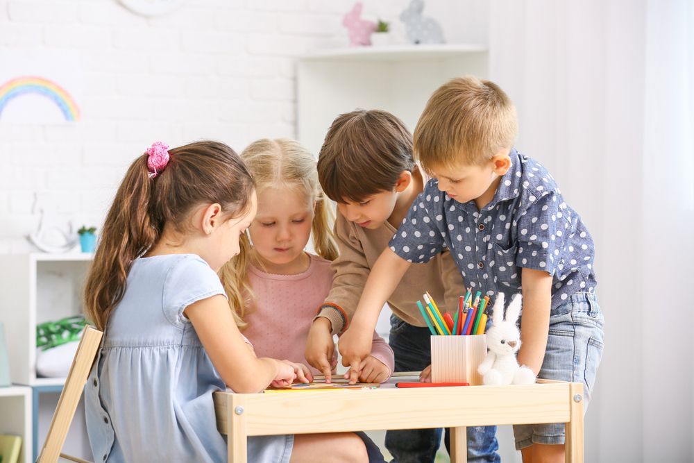 Montessori students sitting at a table working on an activity together in a multi age montessori classroom