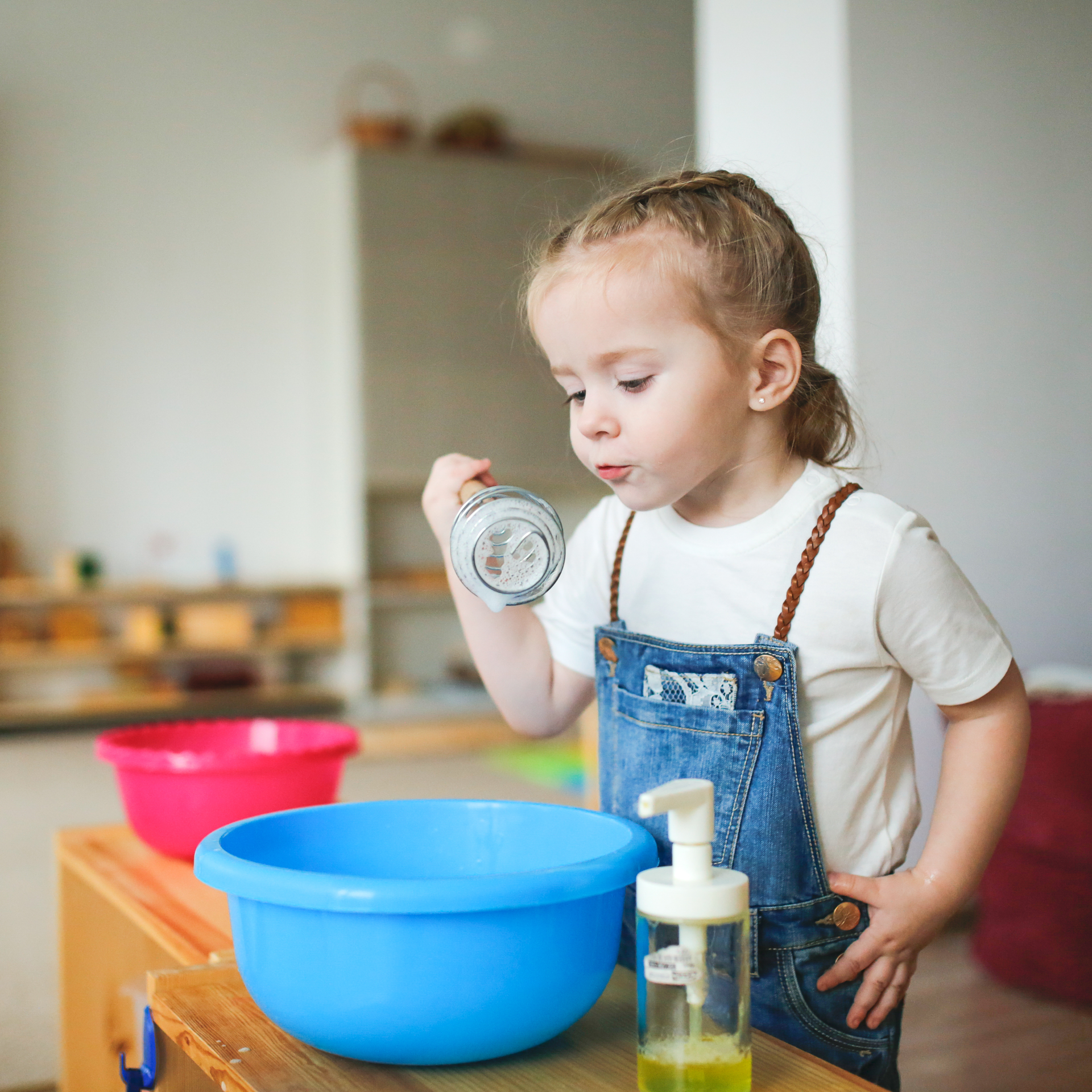 A little girl is pouring liquid into a blue bowl