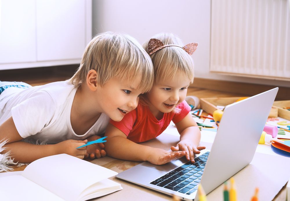 Two children at a Montessori school are using a computer for screen time.