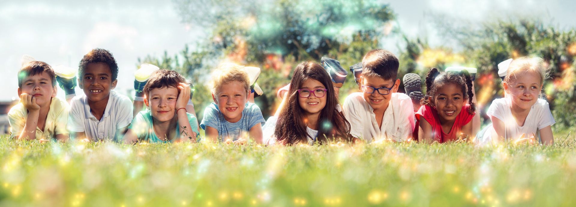 A group of children are laying in a field of grass.