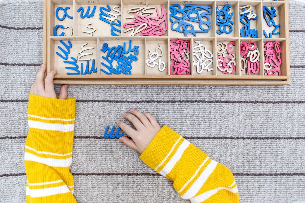 A child is playing with a box of letters and numbers.