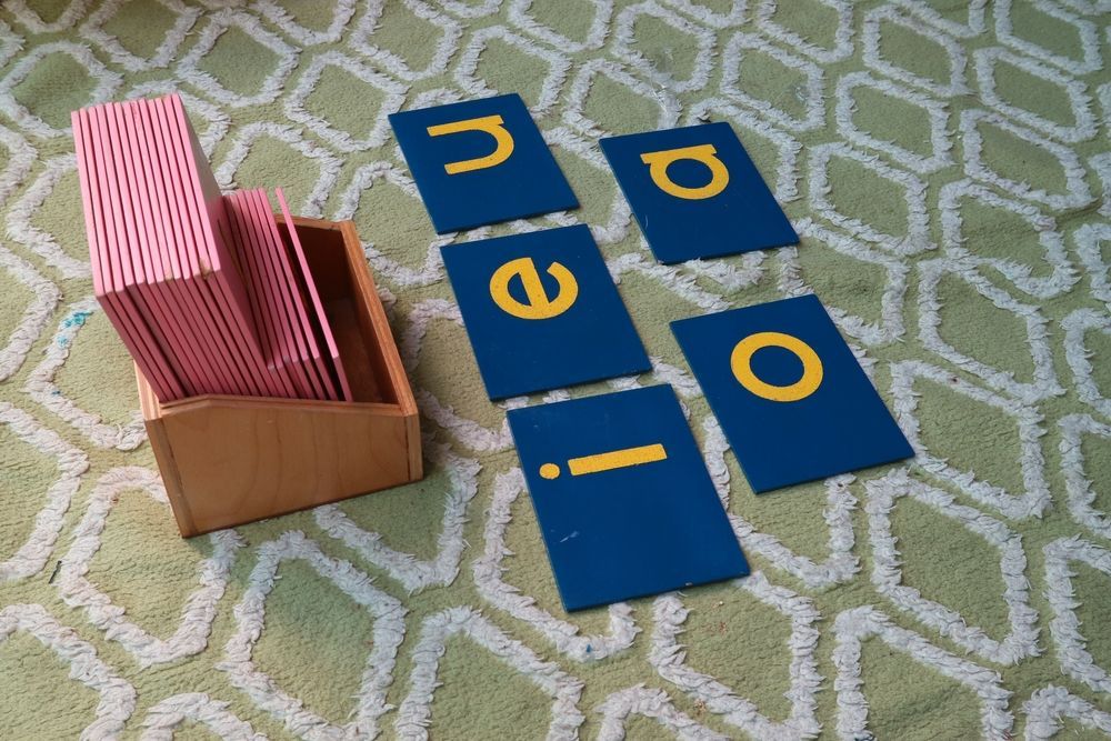 A box of cards with letters on them is sitting on a rug.