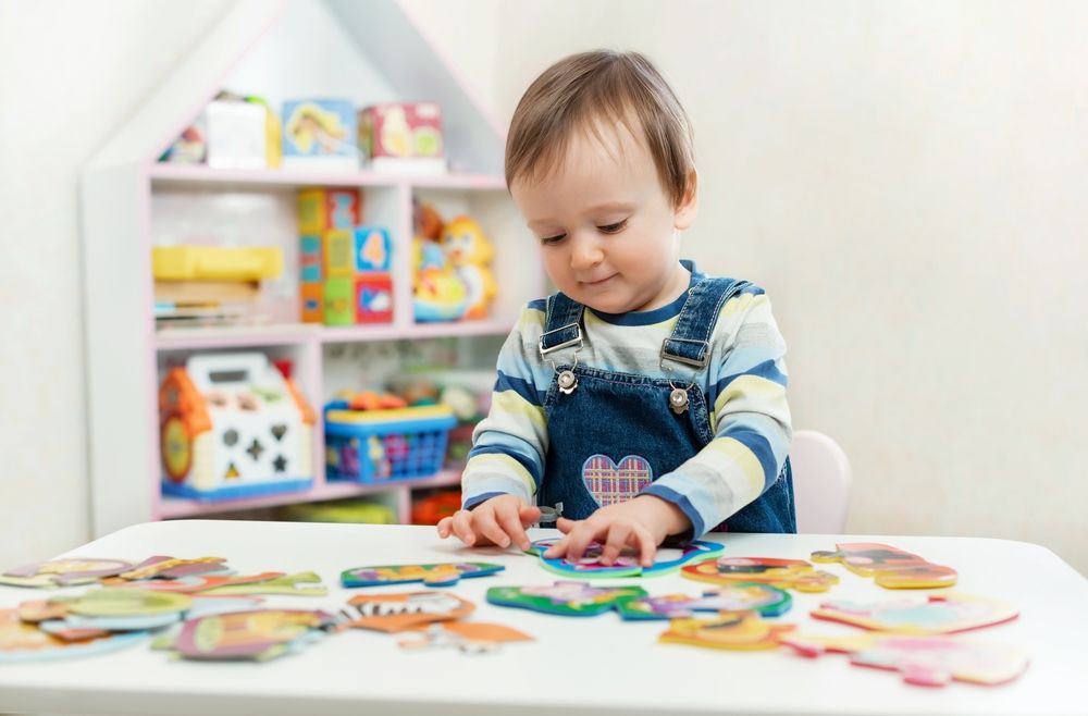 A little boy is sitting at a table playing with puzzles.