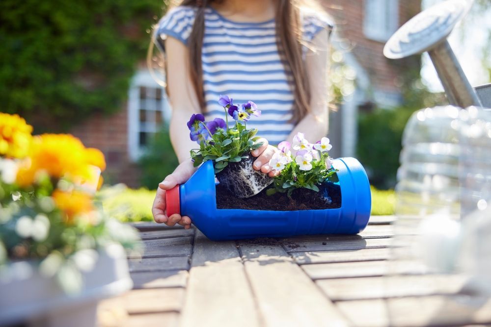 close up of preschooler girl making  a planter out of a recycled plastic bottle