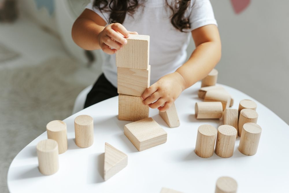 preschooler playing with wooden blocks as a part of building practical life skills