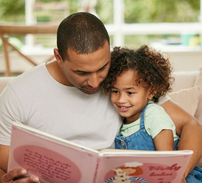 A father is reading a book to a little girl