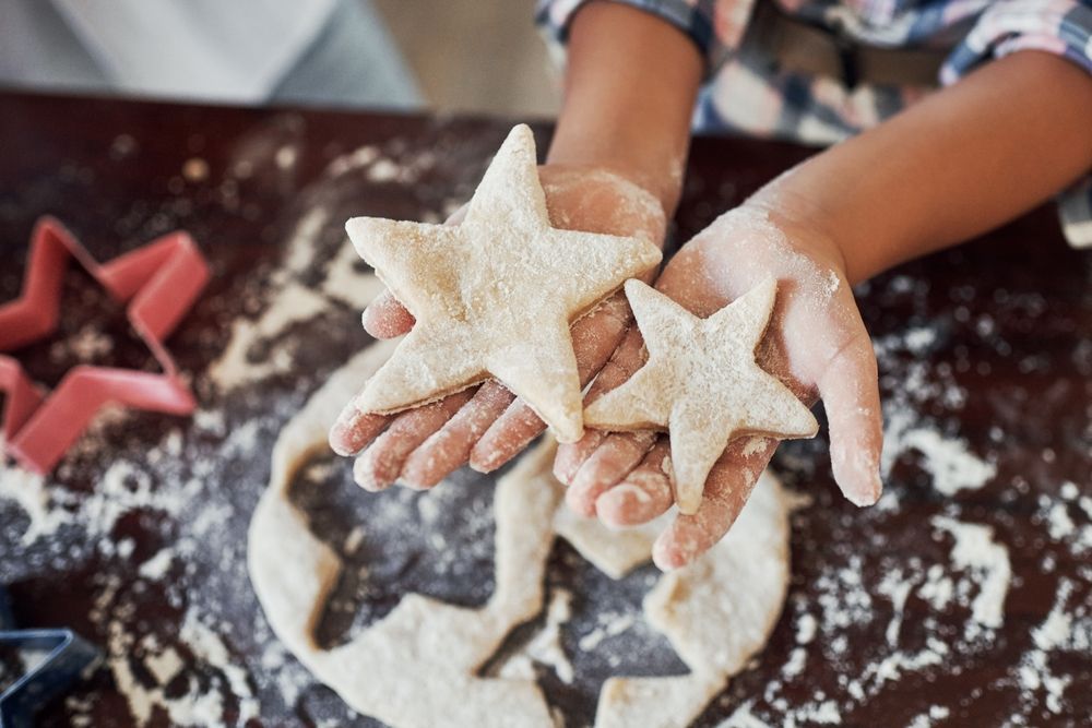 A child is holding three star shaped cookies in her hands.