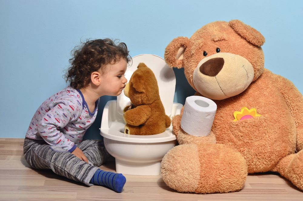 Montessori Child kisses their teddy bear while the teddy practices potty training 