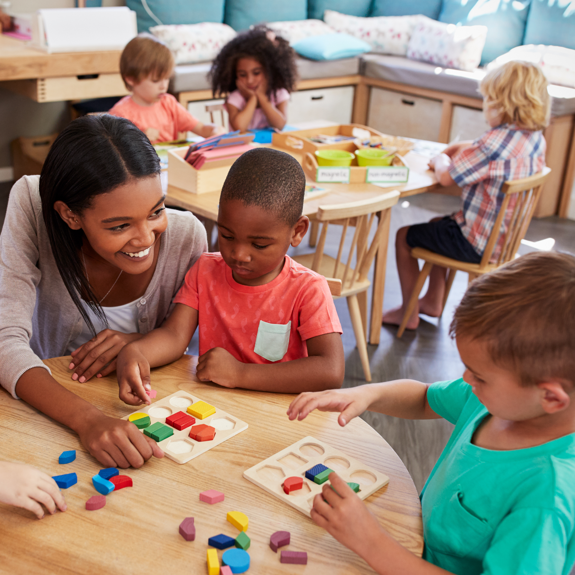 A group of children are sitting around a table playing with toys.