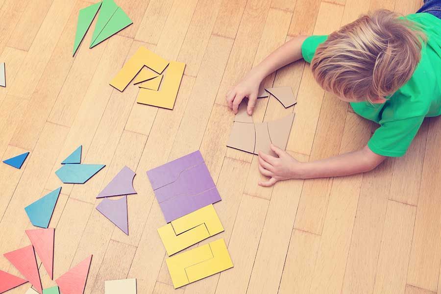 A young boy is laying on the floor playing with puzzles.