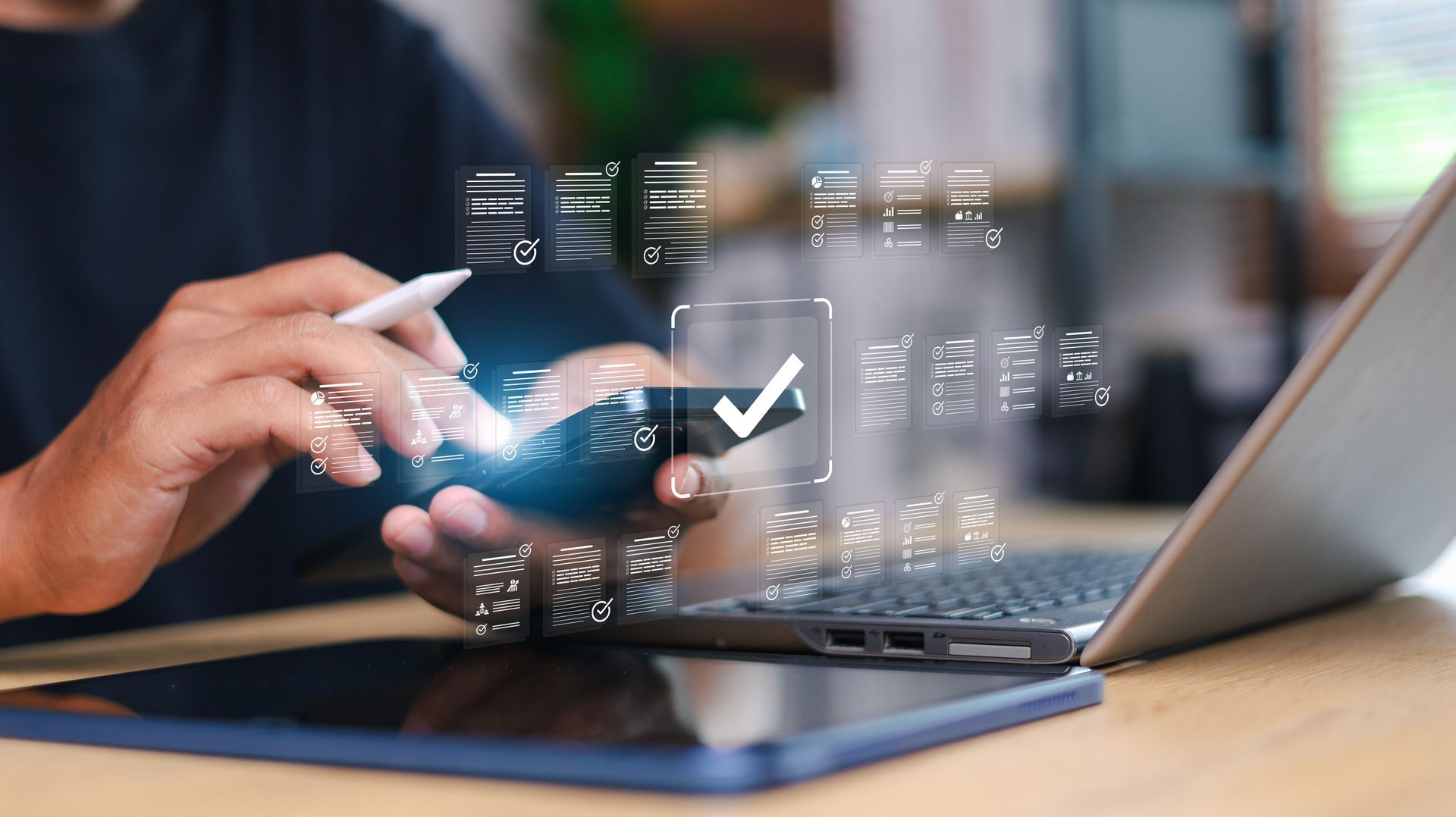 Person using a phone with a digital check mark over it, near a laptop and tablet. Person using a phone with a digital check mark over it, near a laptop and tablet.
