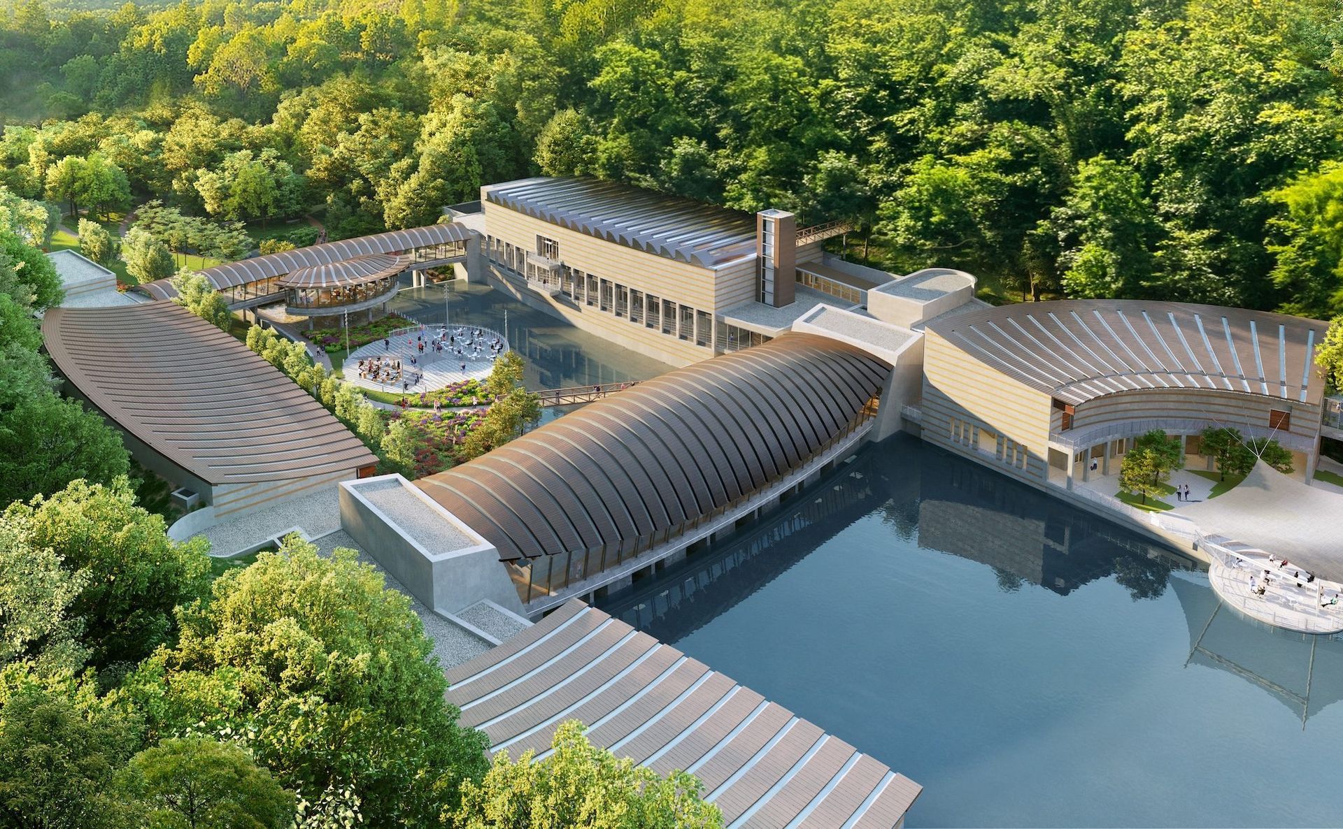 An aerial view of a modern complex with curved roofs, surrounded by dense trees and connected by large water features.