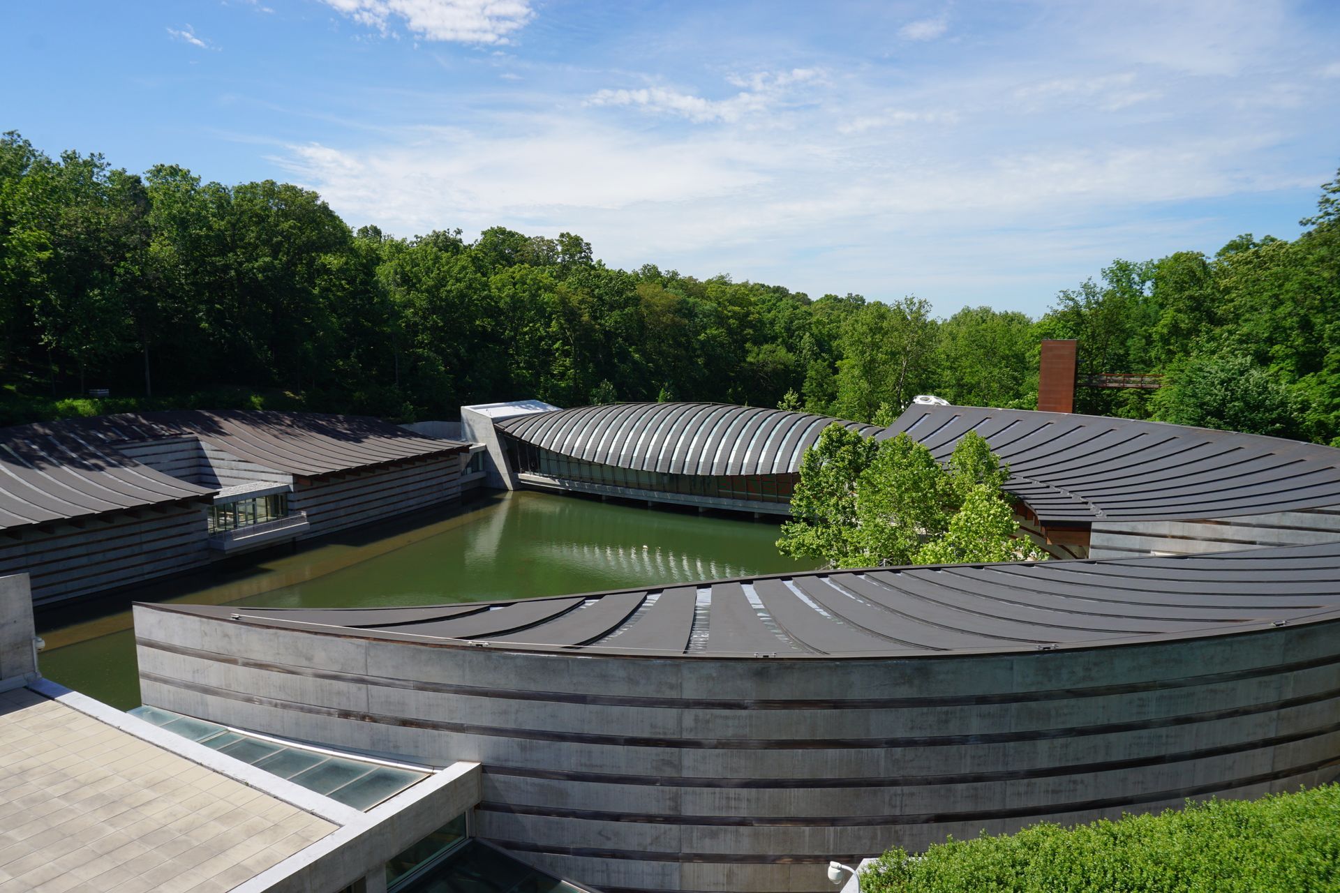 The Crystal Bridges Museum of American Art building, featuring modern, curved architecture set in a wooded landscape.