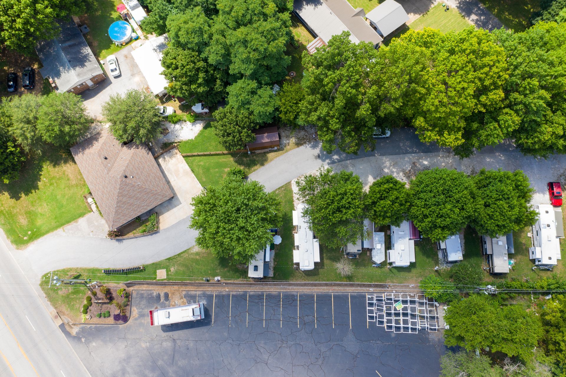 An aerial view of a residential area showing a house, parking lot with a trailer, and several parked mobile homes.