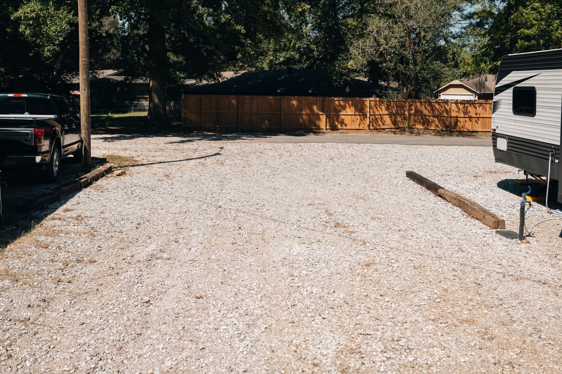 A gravel driveway parking area with a truck on the left and a travel trailer parked on the right.