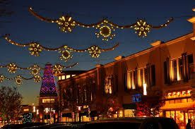 A shopping area at dusk, decorated with glowing, star-shaped string lights draped between warm, lit storefronts.