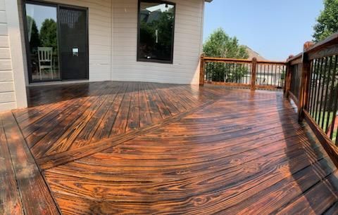 A large wooden deck is sitting in front of a house.