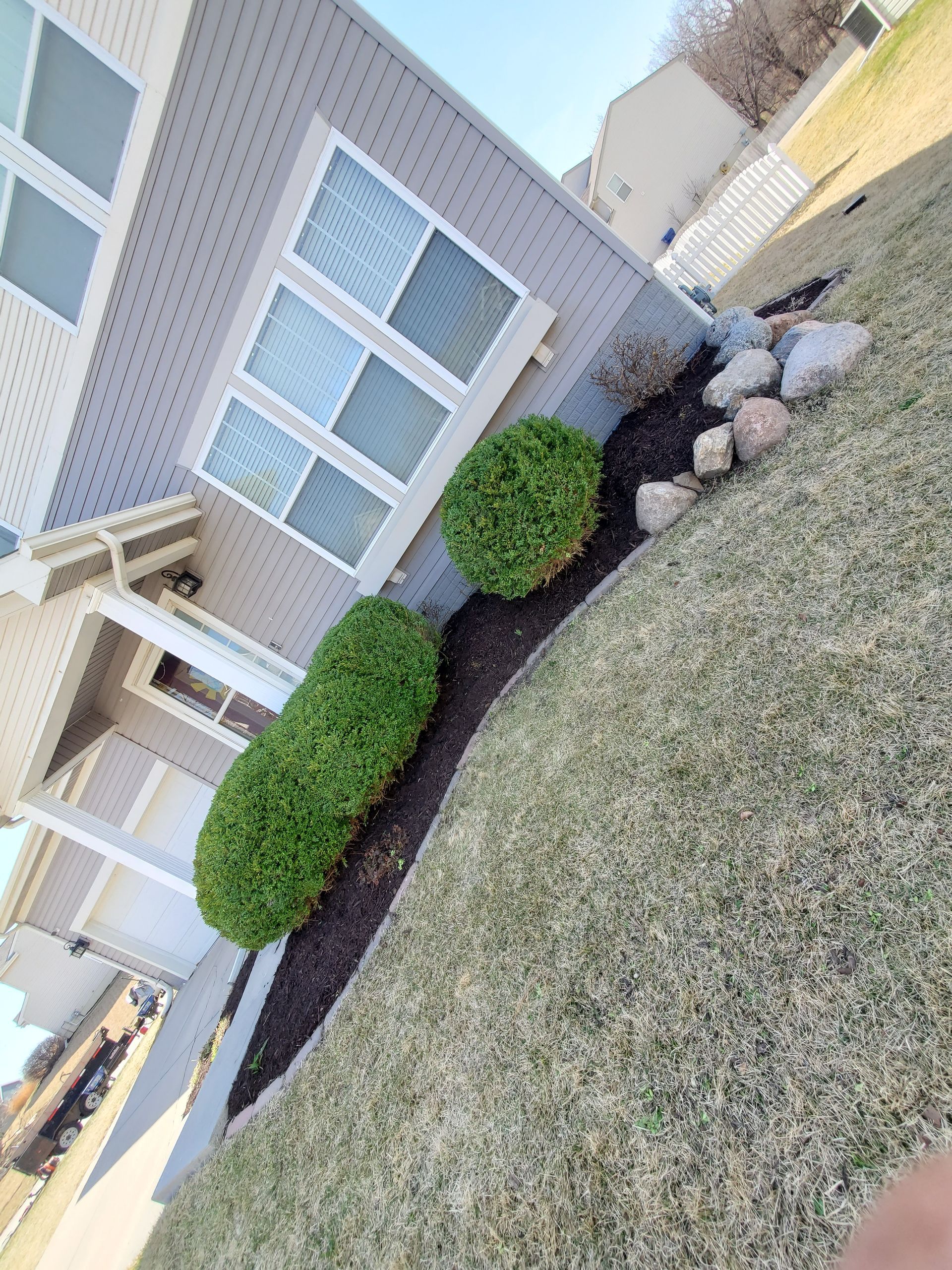 A house with a lot of bushes and rocks in front of it.