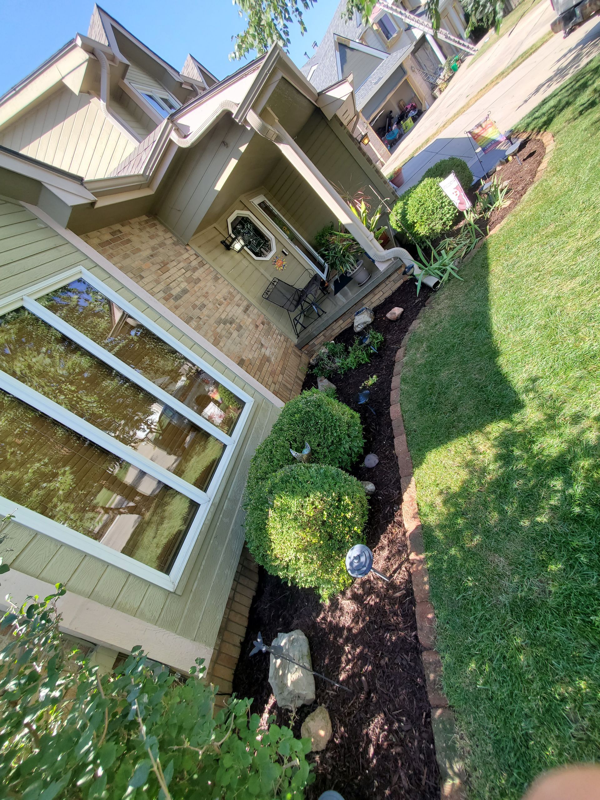 A house with a lush green lawn and bushes in front of it.