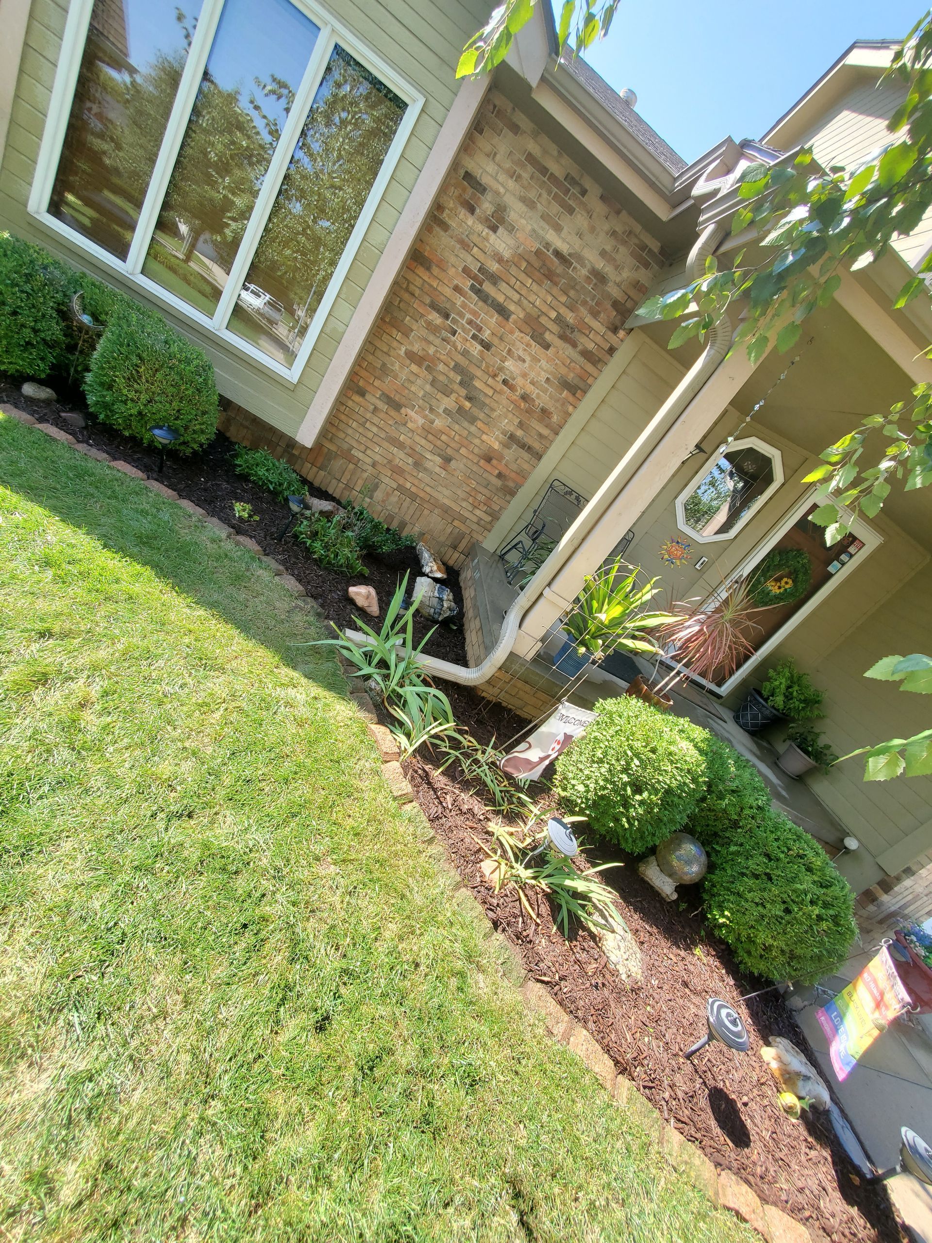 A house with a lush green lawn and bushes in front of it.