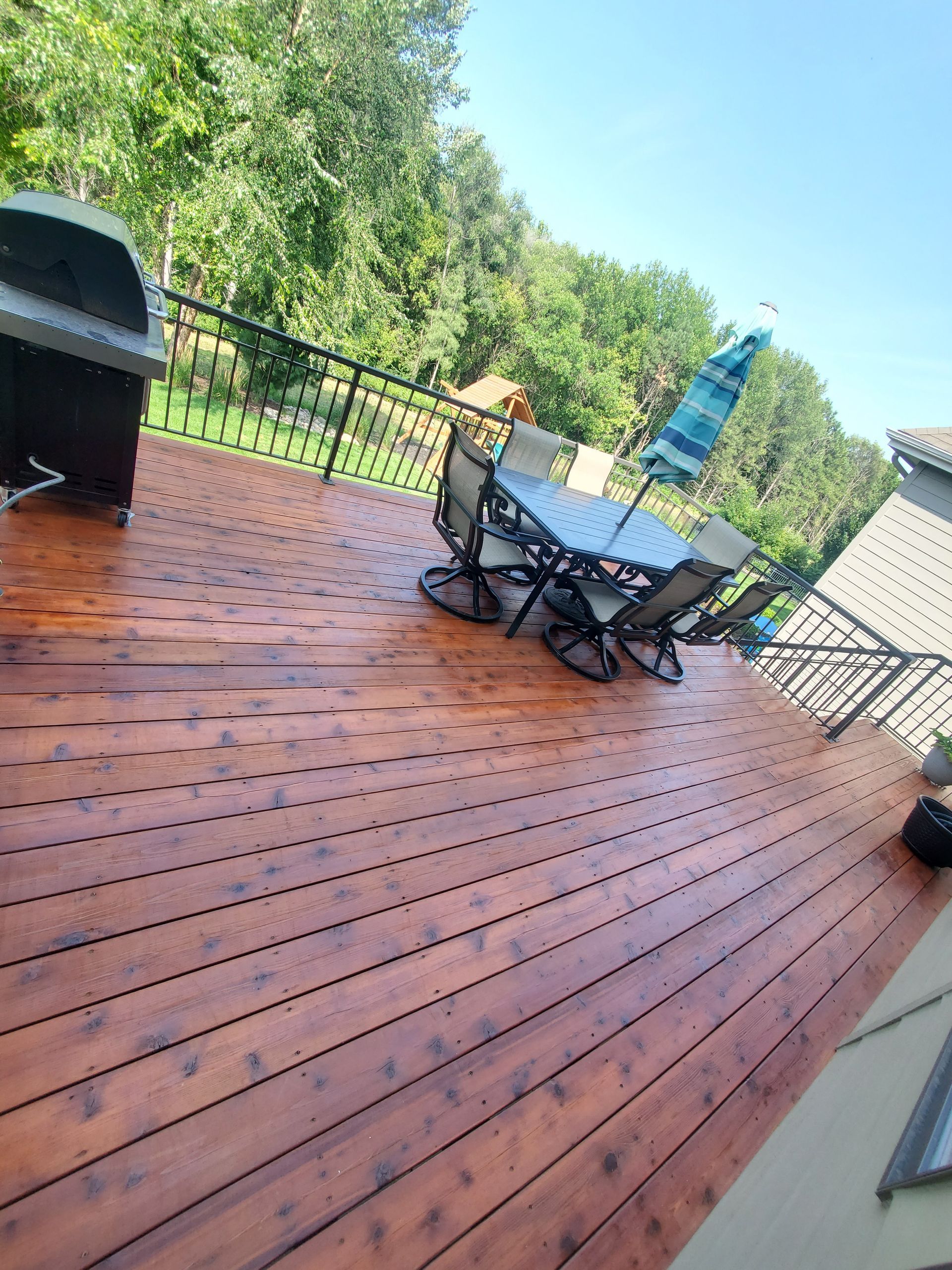 A wooden deck with a table and chairs and a grill.