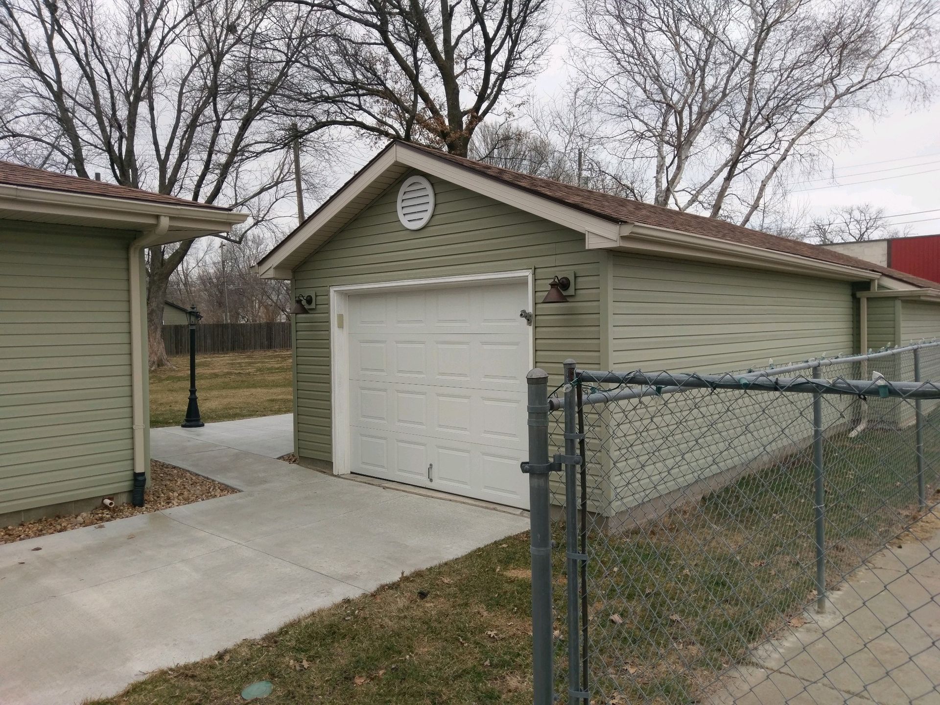 A garage with a white door is behind a chain link fence.