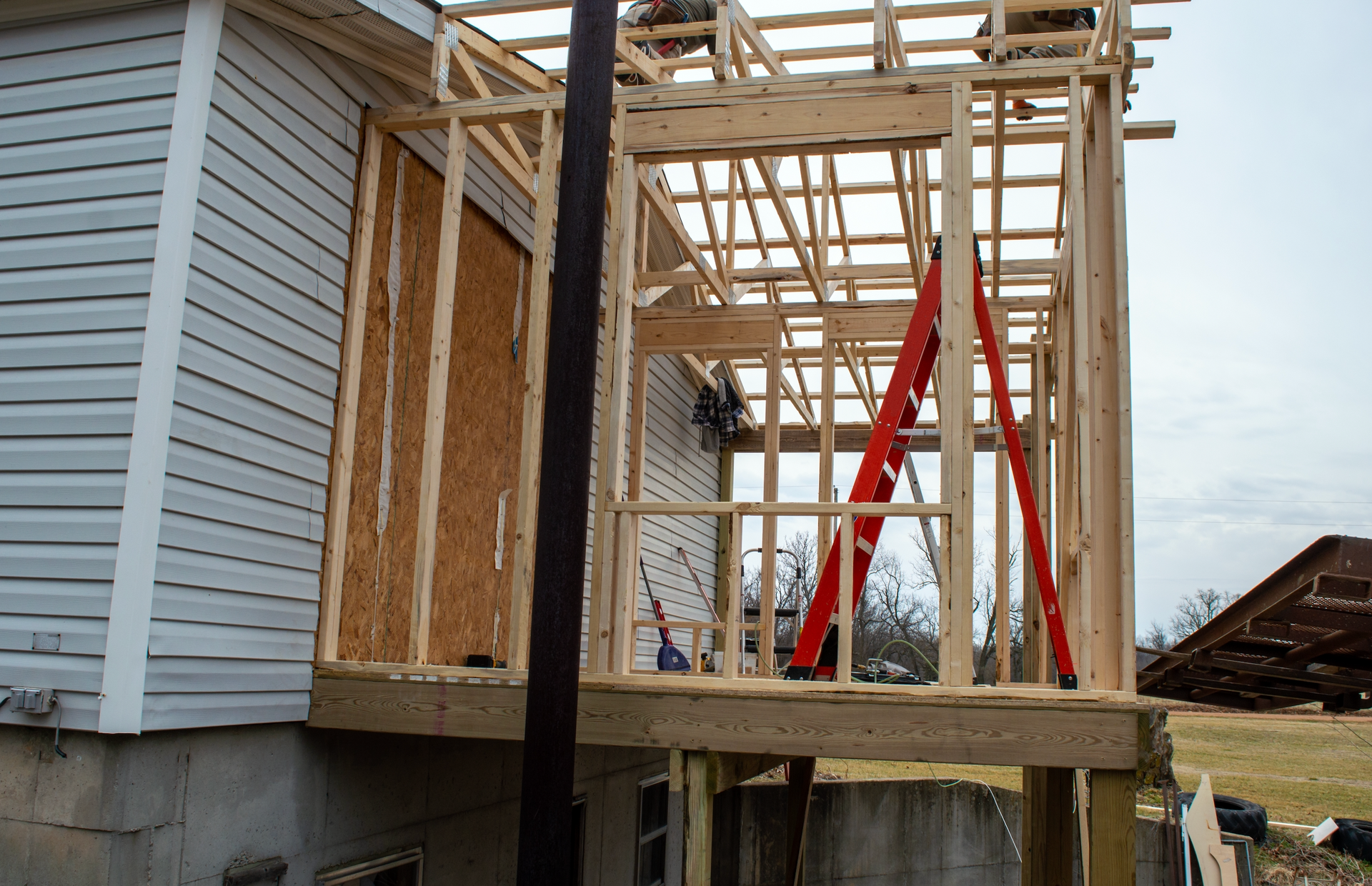 A house under construction with a red ladder in the foreground