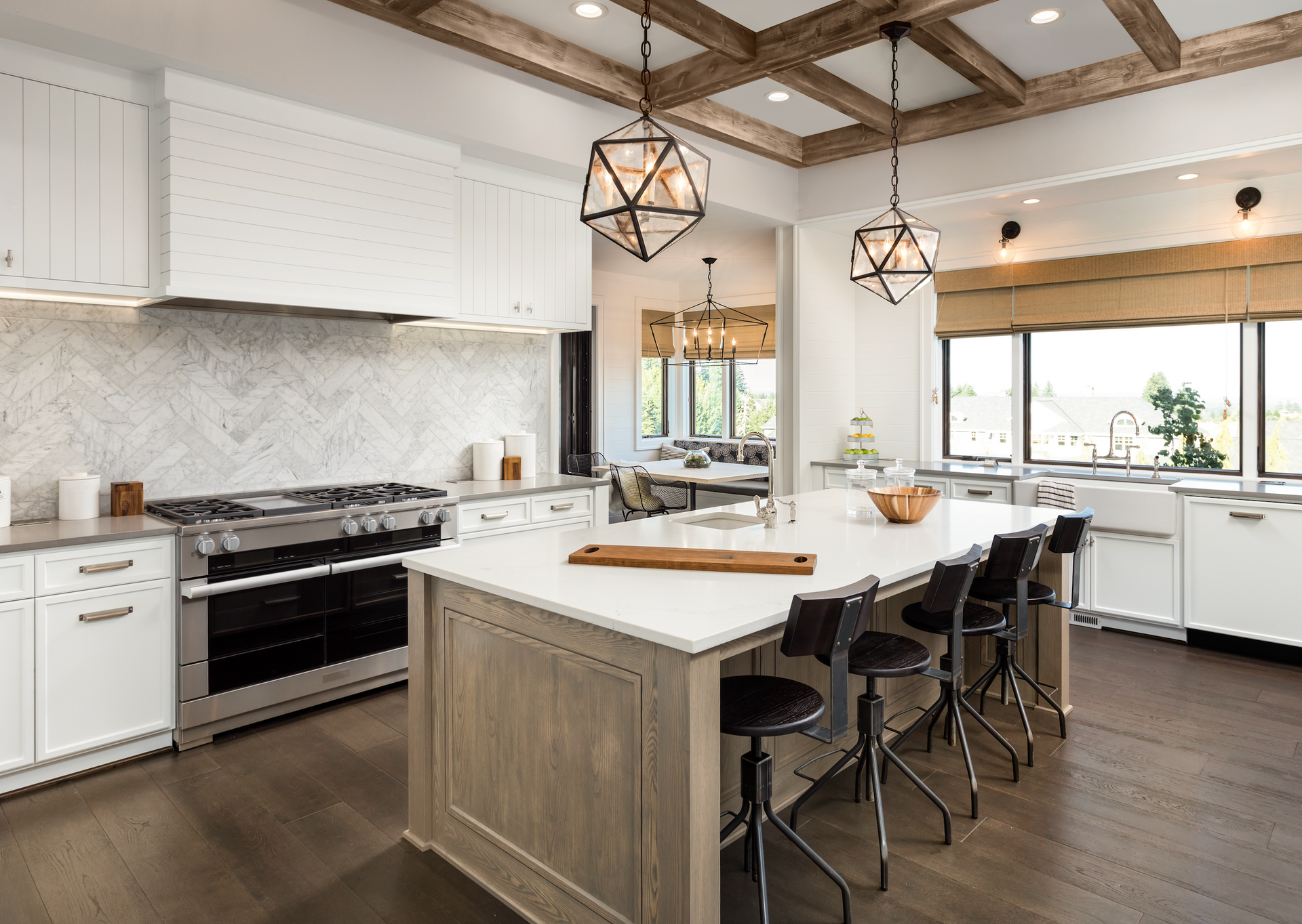 A kitchen with white cabinets , stainless steel appliances , and a large island.