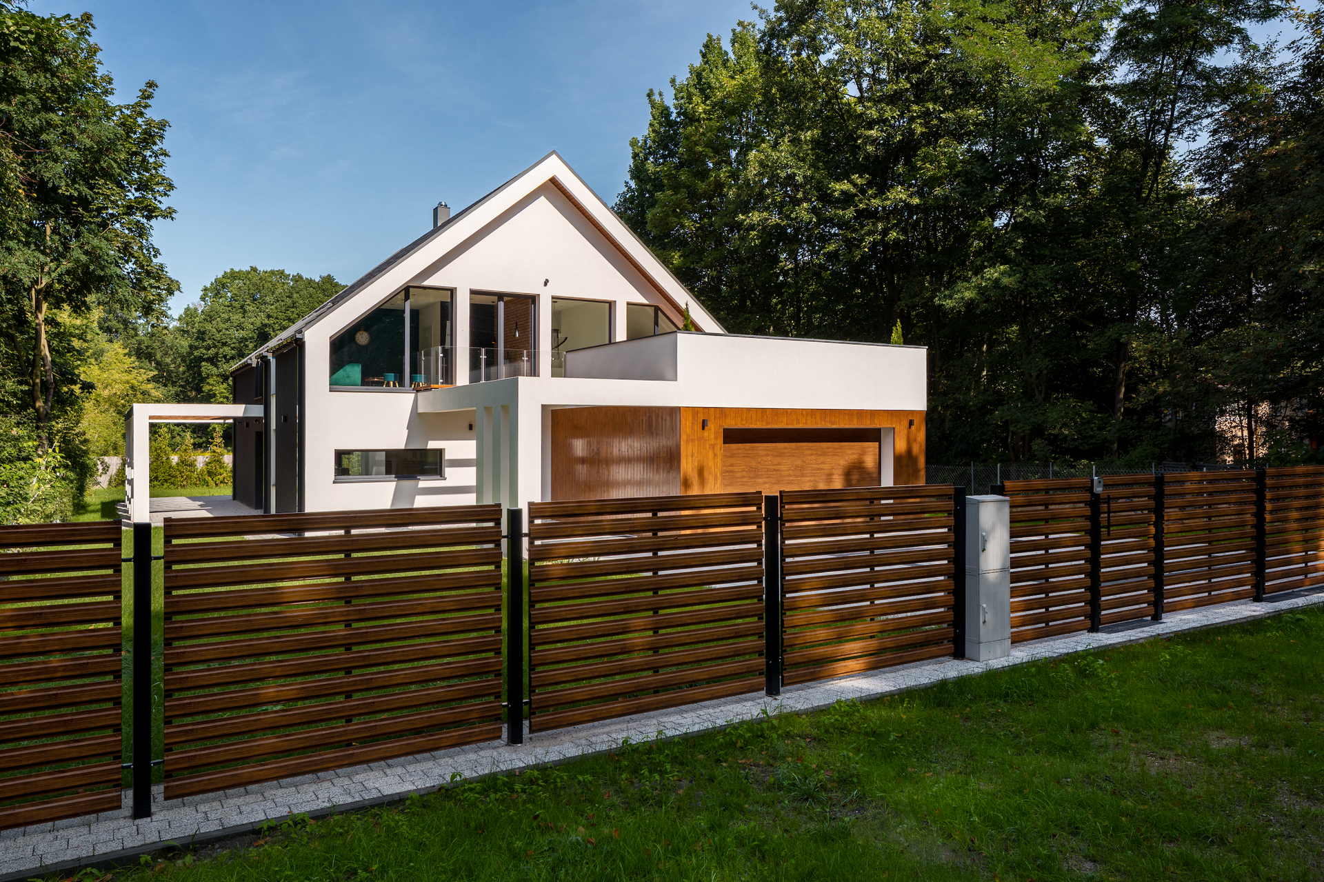 A modern house with a wooden fence in front of it.