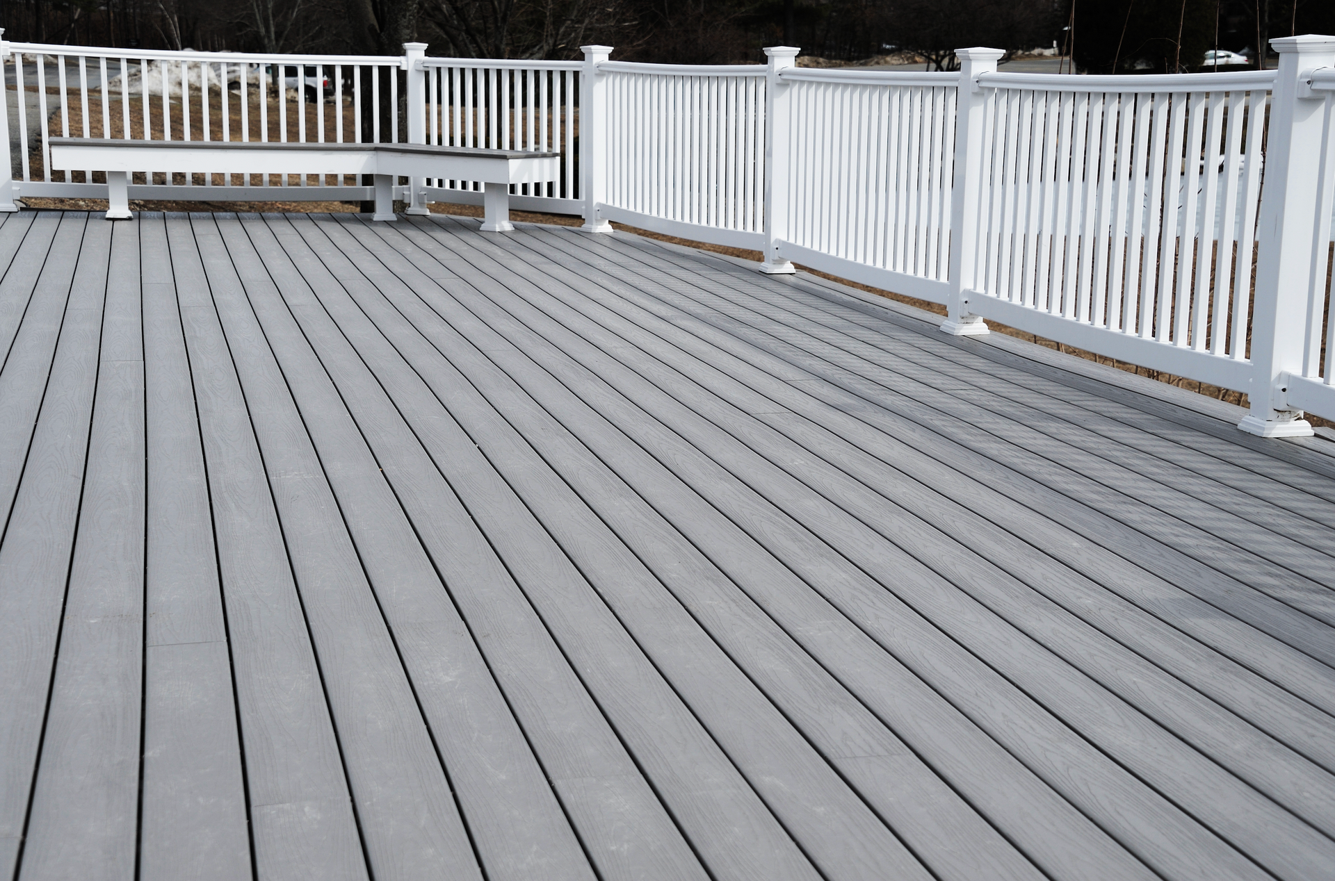 A gray wooden deck with a white railing