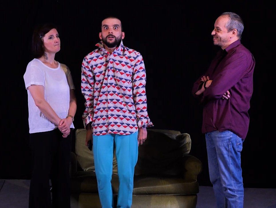 un homme et deux femmes se tiennent côte à côte devant un canapé.