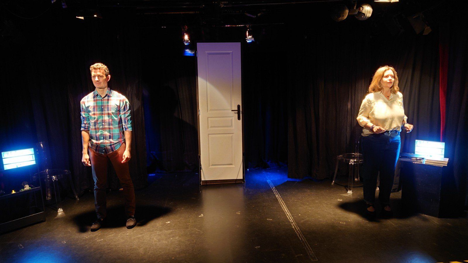 un homme et une femme se tiennent sur une scène devant une porte.