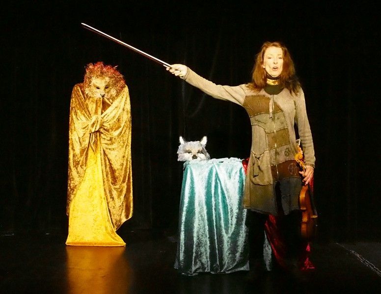Une femme tient une baguette devant un chat sur une table