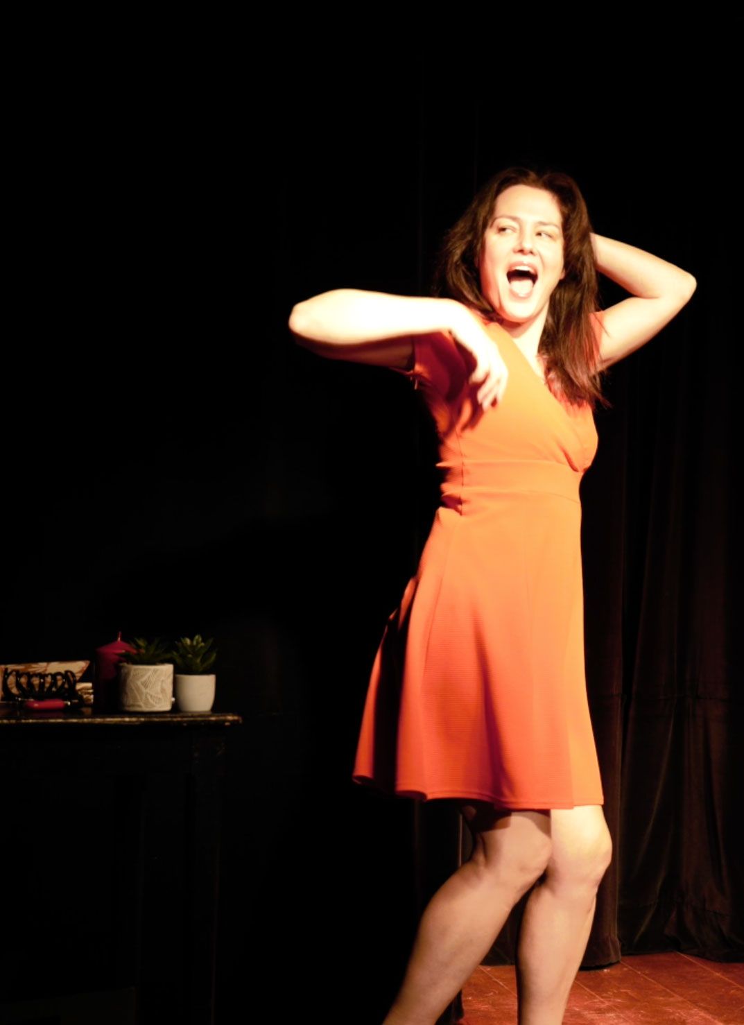 Une femme en robe orange danse sur une scène