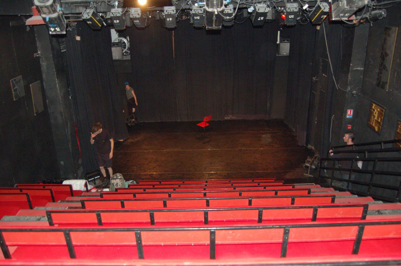 un théâtre vide avec des sièges rouges et une scène noire