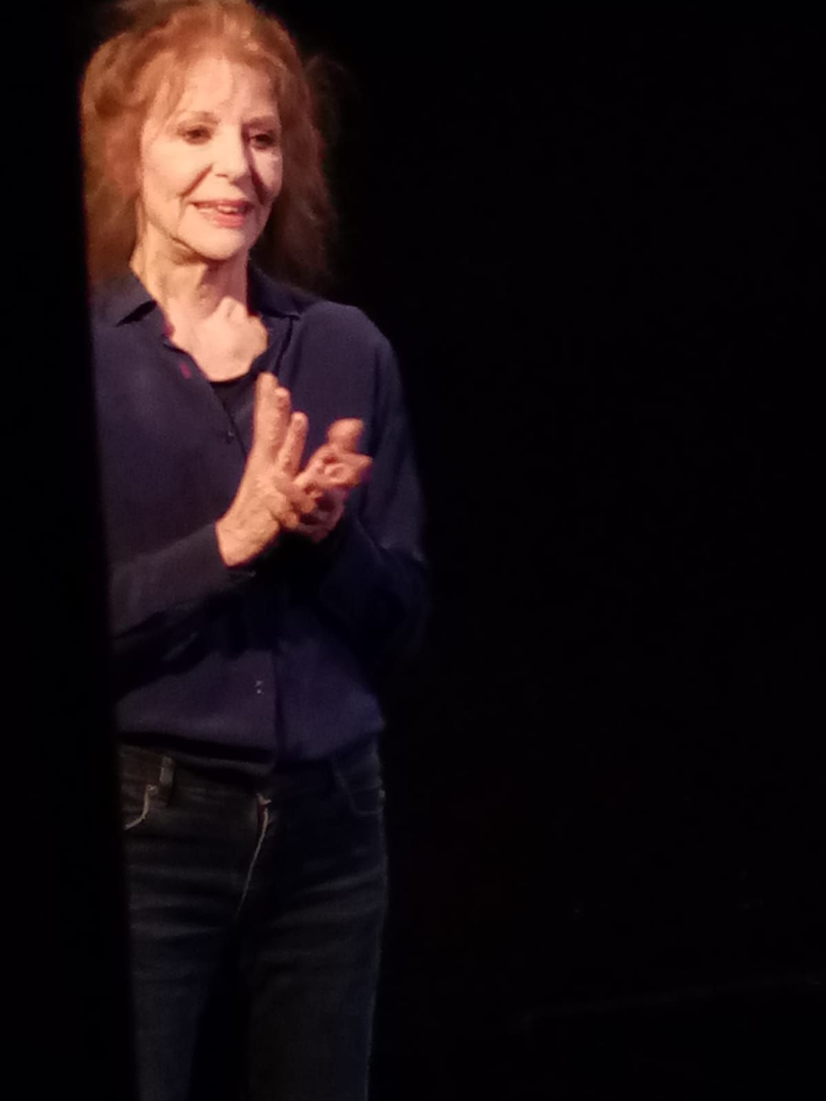 Une femme est debout sur une scène et frappe dans ses mains.