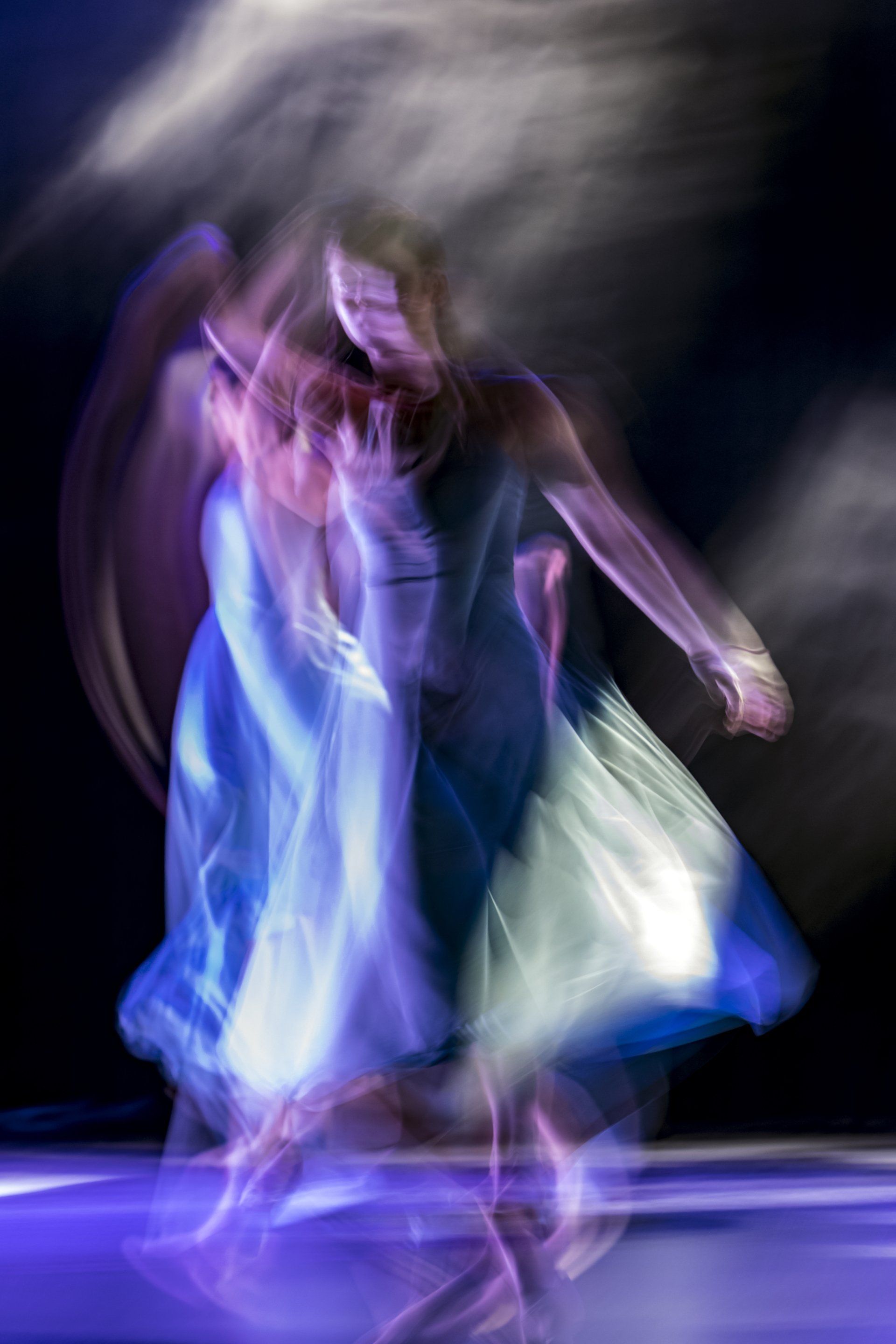une photo floue d'une femme vêtue d'une robe bleue dansant sur une scène.