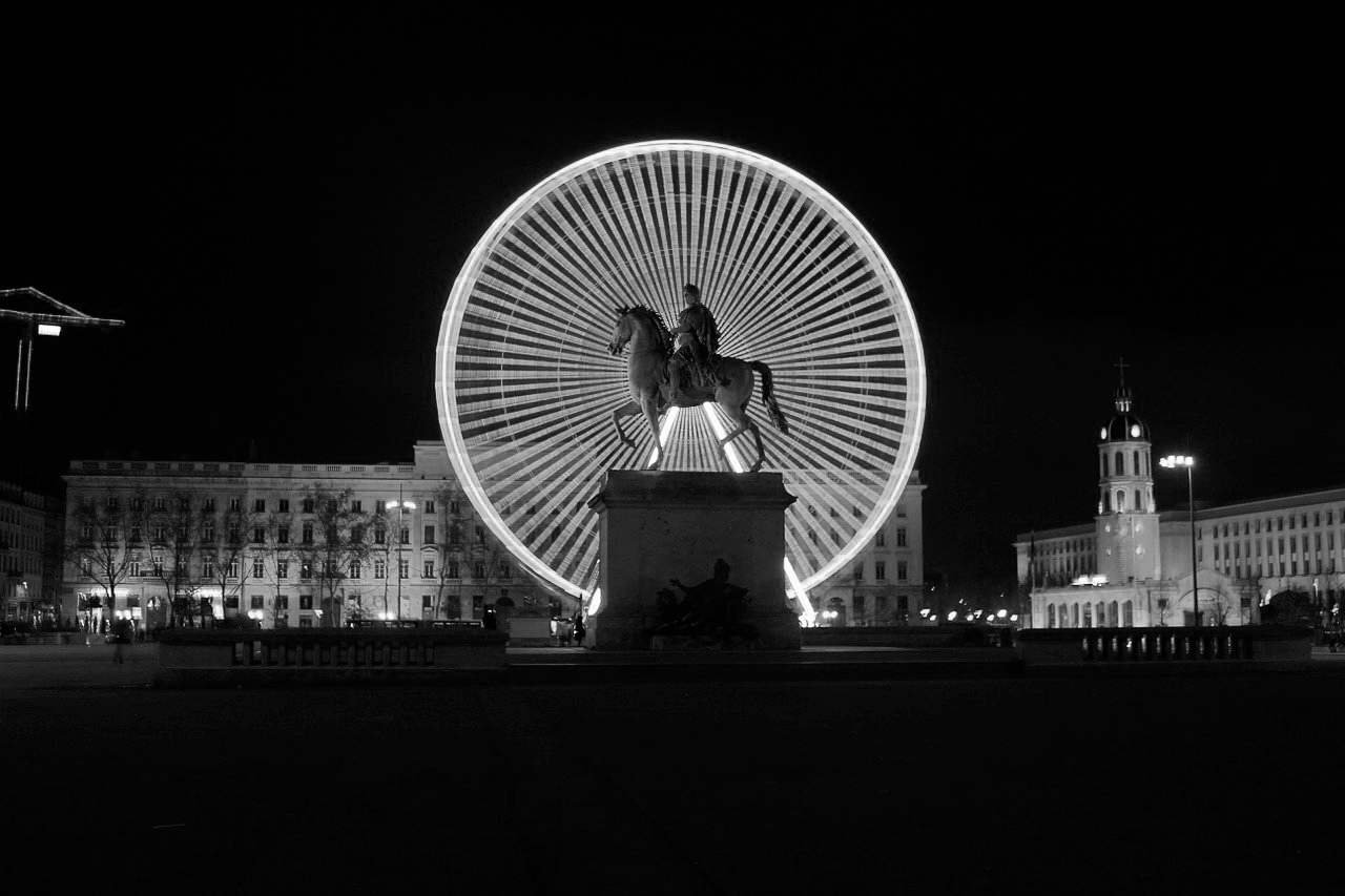 photo d'une statut à Lyon place Bellecour d'un homme sur un cheval devant une grande roue en noir et blanc