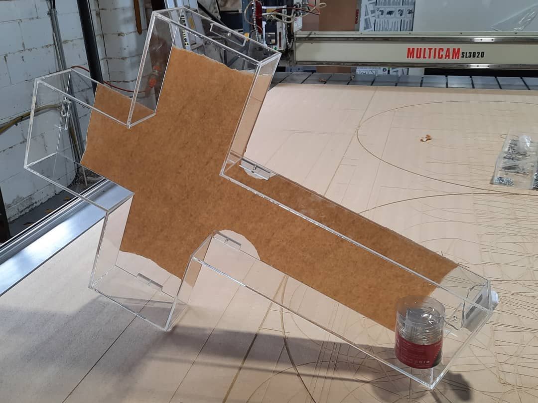 A Clear Acrylic Cross is Sitting on Top of a Wooden Table — Coastal Plastics In Tweed Heads South, NSW