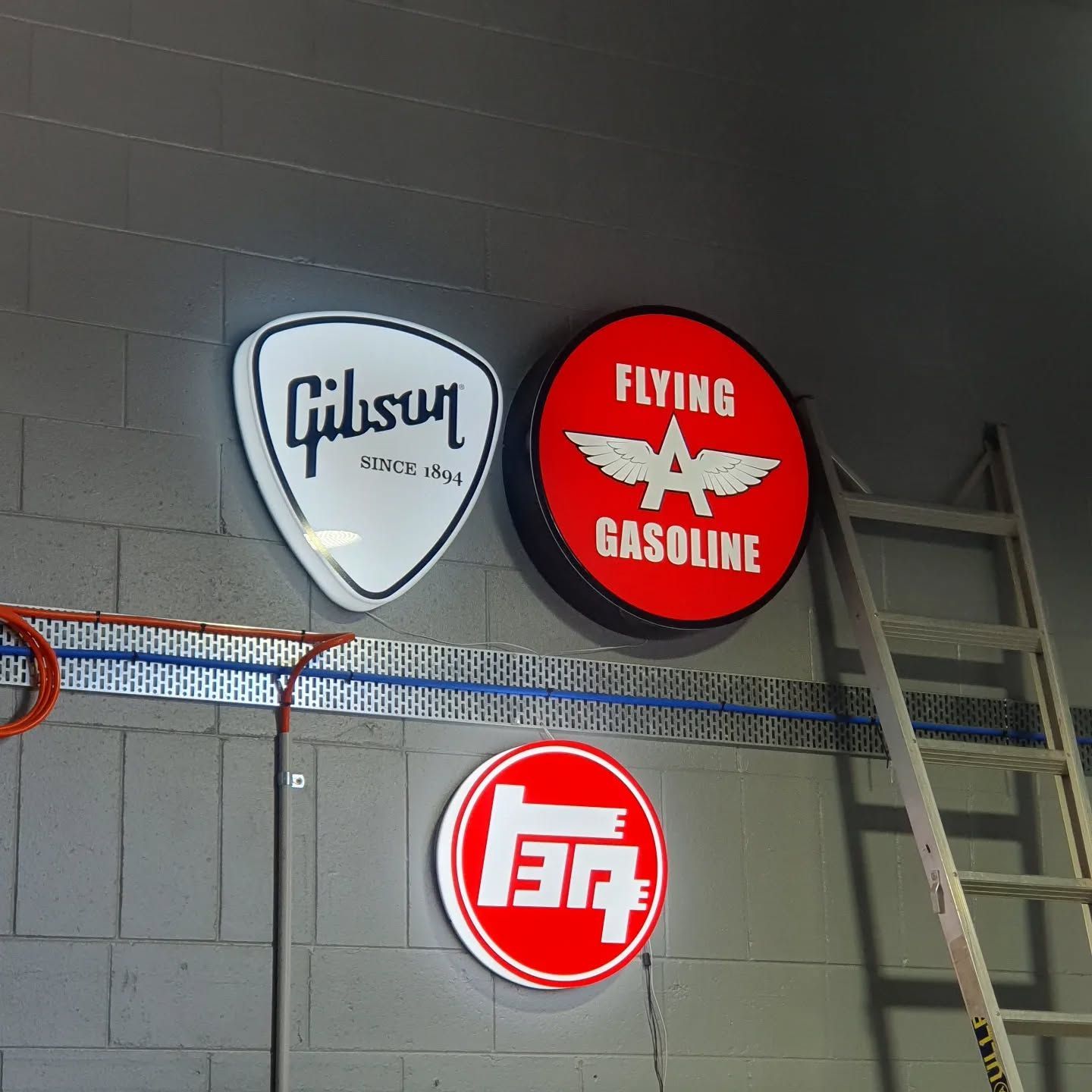 A Gibson Guitar Pick Sits Next to a Flying a Gasoline Sign — Coastal Plastics In Tweed Heads South, NSW