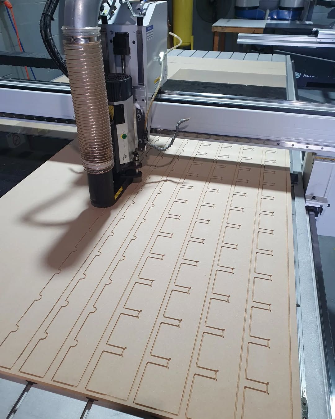 A Machine is Cutting a Piece of Wood on a Table — Coastal Plastics In Tweed Heads South, NSW
