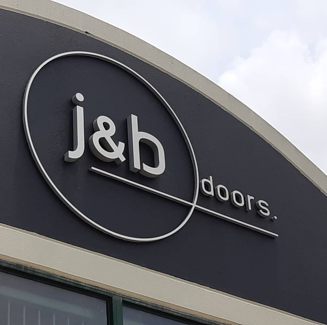 A Sign on a Building That Says J & B Doors — Coastal Plastics In Tweed Heads South, NSW