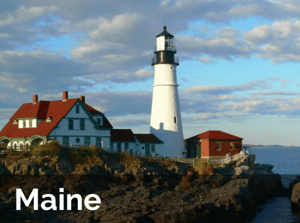 A lighthouse sits on top of a rocky cliff in maine