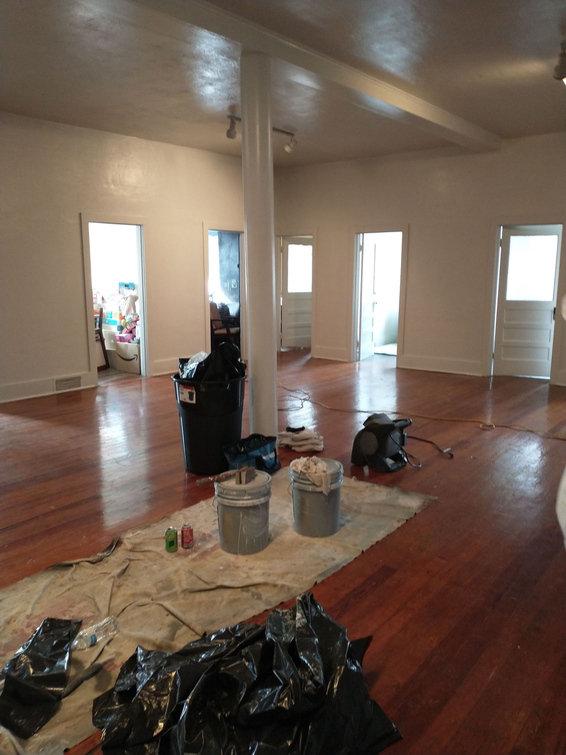 A large empty room with hardwood floors and white walls.