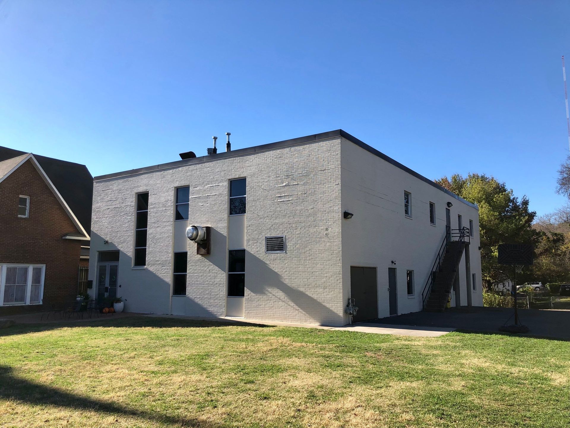 A large white brick building with stairs leading up to it is sitting on top of a lush green field.