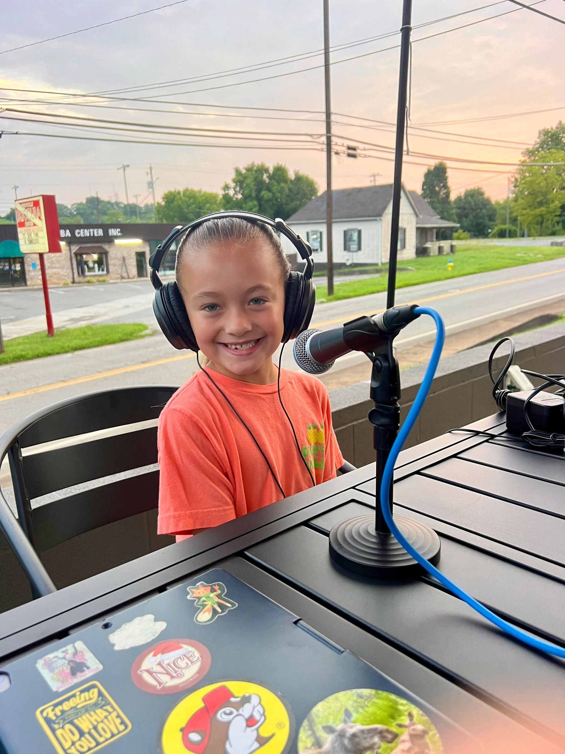 A young boy wearing headphones is sitting at a table in front of a microphone.