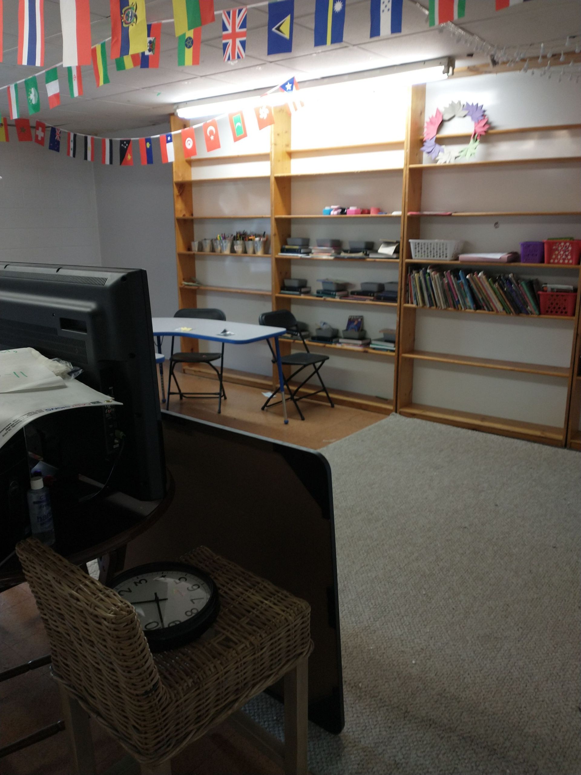 A clock sits on a chair in a room with flags hanging from the ceiling